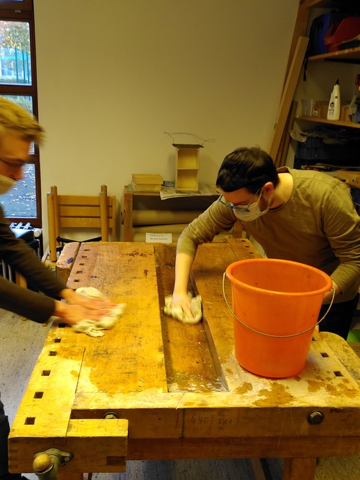 Zwei Schüler arbeiten in der Schulwerkstatt und putzen (vergrößerte Bildansicht wird geöffnet)
